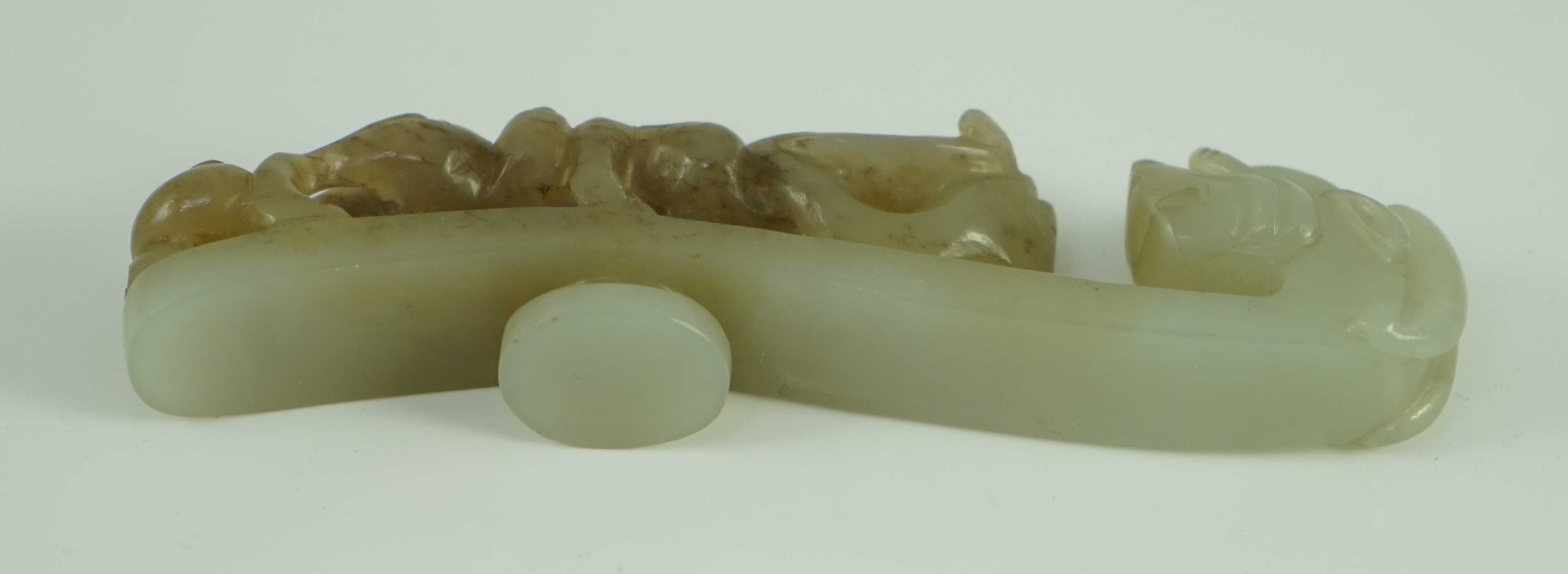 A Chinese pale celadon and brown jade ‘dragon’ belt hook, 18th/19th century 10.7 cm long